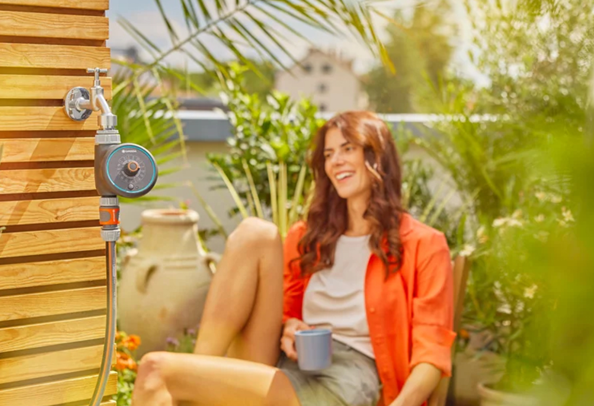 Απεικονίζεται γυναίκα καθισμένη δίπλα στον προγραμματιστή να κρατάει μια κούπα.